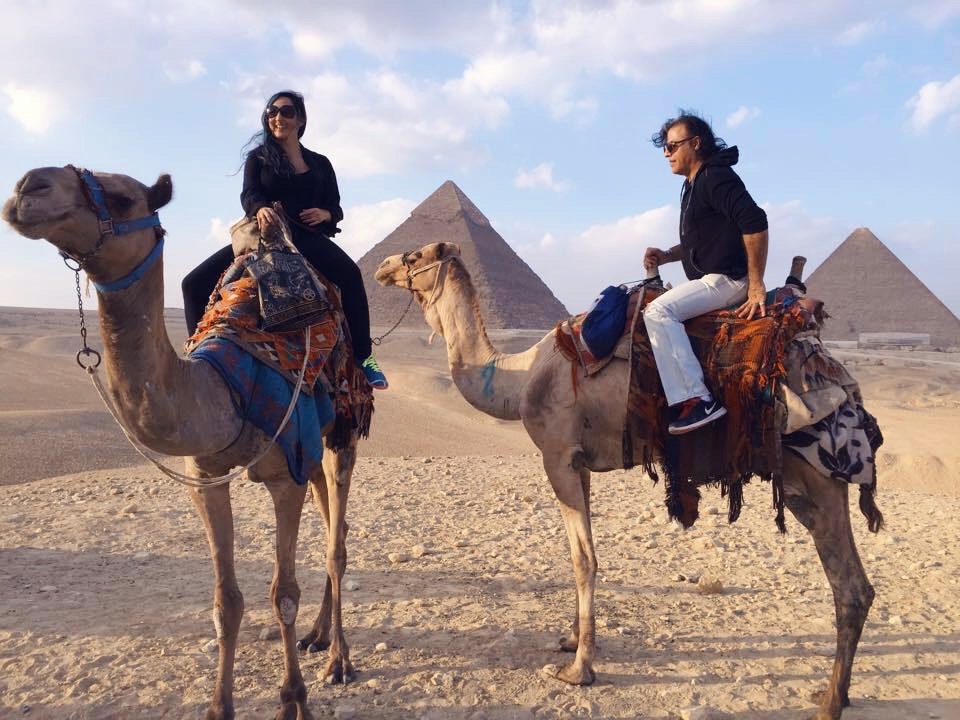 Unforgettable experiences in Egypt: a couple riding camels in the Sahara Desert with a view of the Pyramids