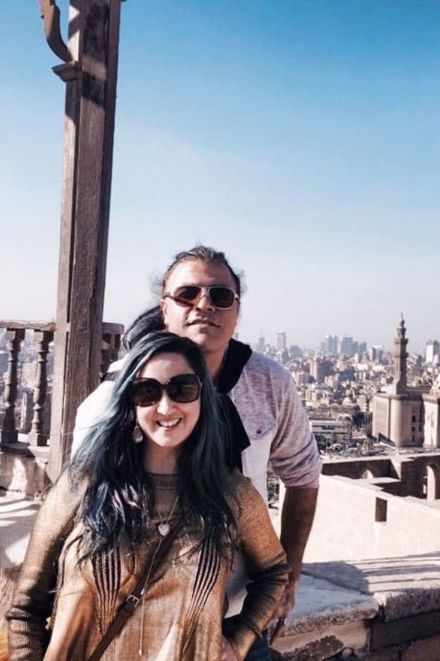 A couple standing together with the Cairo skyline in the background, taken from the terrace of the Mohammed Ali Mosque in Egypt.