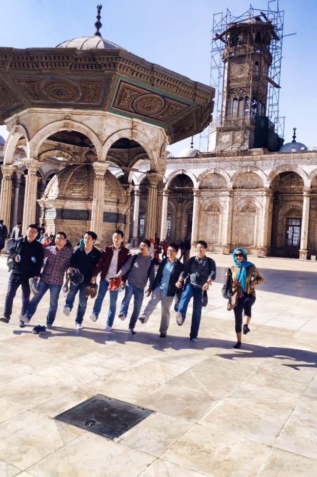 A group of people posing in front of the Mohammed Ali Mosque in Cairo, Egypt, capturing a fun and memorable moment during their visit.
