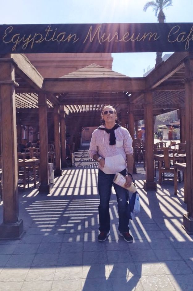 A man standing outside the Egyptian Museum Cafe in Cairo, Egypt, preparing to explore the museum's rich history and culture.