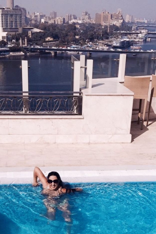 A woman relaxing in a rooftop pool overlooking the Nile River and the cityscape of Cairo, Egypt.