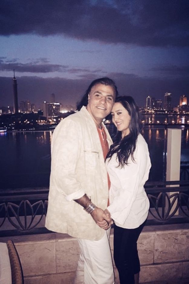 A couple posing together at night with the Nile River and Cairo skyline illuminated in the background, capturing a romantic moment in Egypt.
