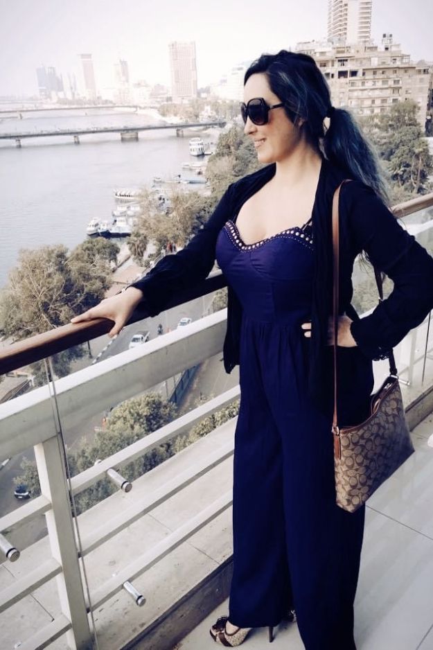 A woman standing on a balcony overlooking the Nile River and the Cairo skyline, enjoying the view in Egypt.