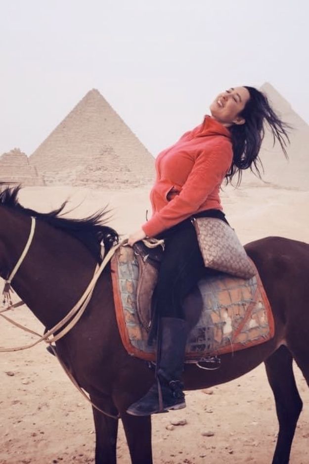 A woman enjoying horseback riding in front of the Pyramids of Giza, capturing a joyful and adventurous moment in Egypt.