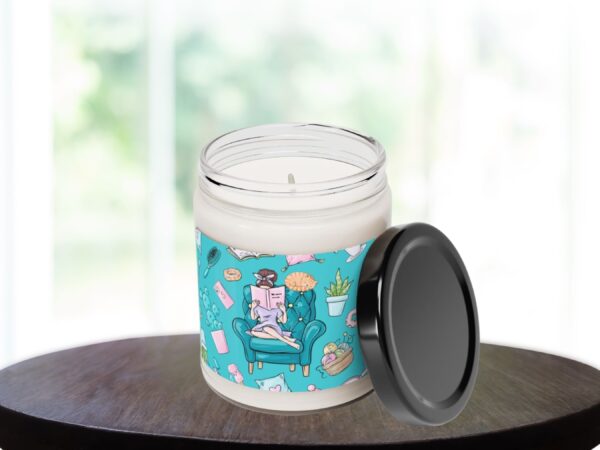 Scented candle with flame against window backdrop
