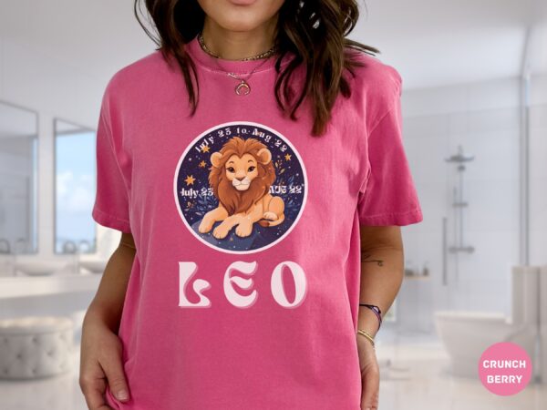 Woman wearing a Crunch Berry Comfort Colors 1717 t-shirt with a Leo Zodiac design featuring a cute lion illustration, stars, and the dates "July 23 to Aug 22."