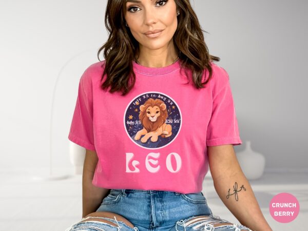 Woman wearing a Crunch Berry Comfort Colors 1717 t-shirt with a Leo Zodiac design featuring a cute lion illustration, stars, and the dates "July 23 to Aug 22."