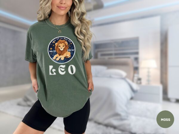 Woman wearing a Moss Comfort Colors 1717 t-shirt with a Leo Zodiac design featuring a cute lion illustration, stars, and the dates "July 23 to Aug 22."