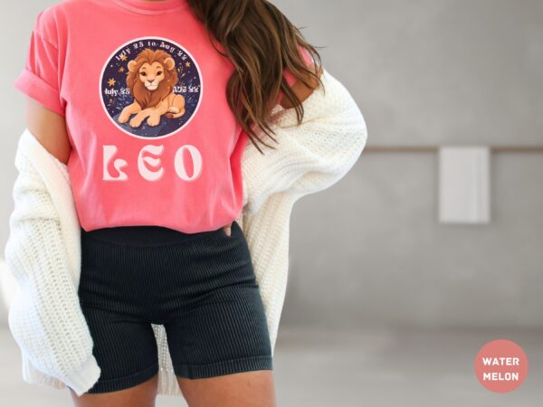 Woman wearing a Watermelon Comfort Colors 1717 t-shirt with a Leo Zodiac design featuring a cute lion illustration, stars, and the dates "July 23 to Aug 22."