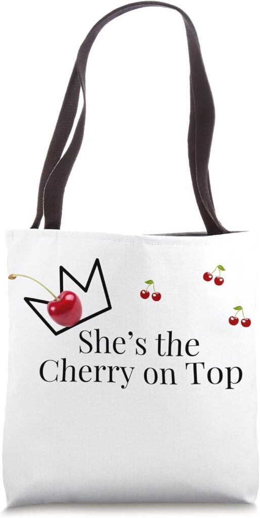 Elegant white tote bag featuring cherry design and 'She’s the Cherry on Top' text—perfect for trendy fashion lovers.
