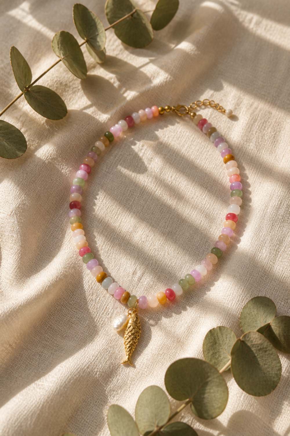 colorful gemstone beaded fish necklace with pearl charm flat lay boho coastal aesthetic jewelry